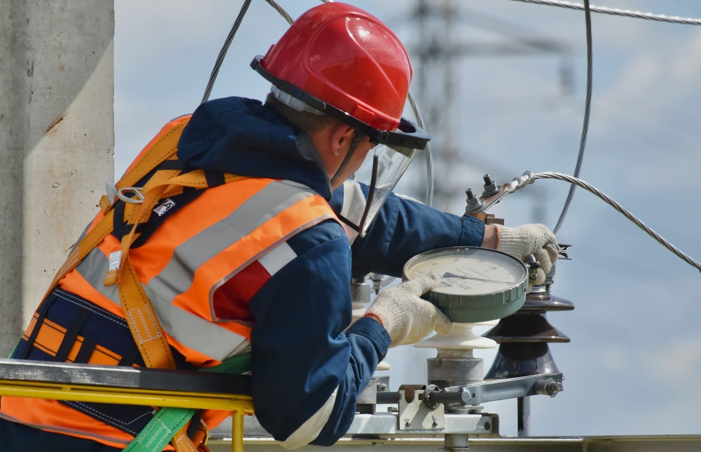 Technik w kamizelce ochronnej reguluje sprzęt elektryczny na zewnątrz.