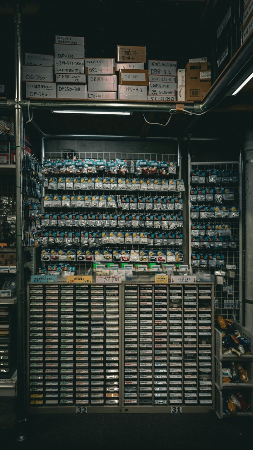 Małe części elektroniczne w plastikowych woreczkach na kratce ściennej.